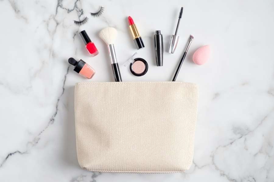 Une élégante trousse de maquillage ouverte sur un fond en marbre, laissant dépasser divers pinceaux et cosmétiques.