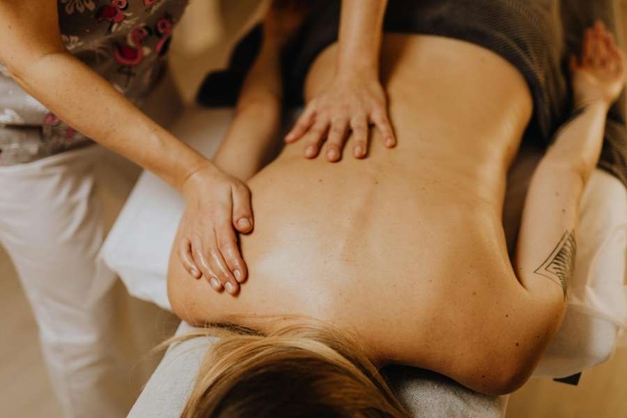 Praticienne effectuant des manœuvres fluides sur le dos d'une personne lors d'un massage balinais relaxant.